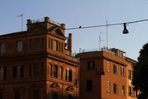 Foto di due palazzi della zona di Roma vicino Piazza Bologna. Un uccellino è poeticamente posato su un cavo della luce.